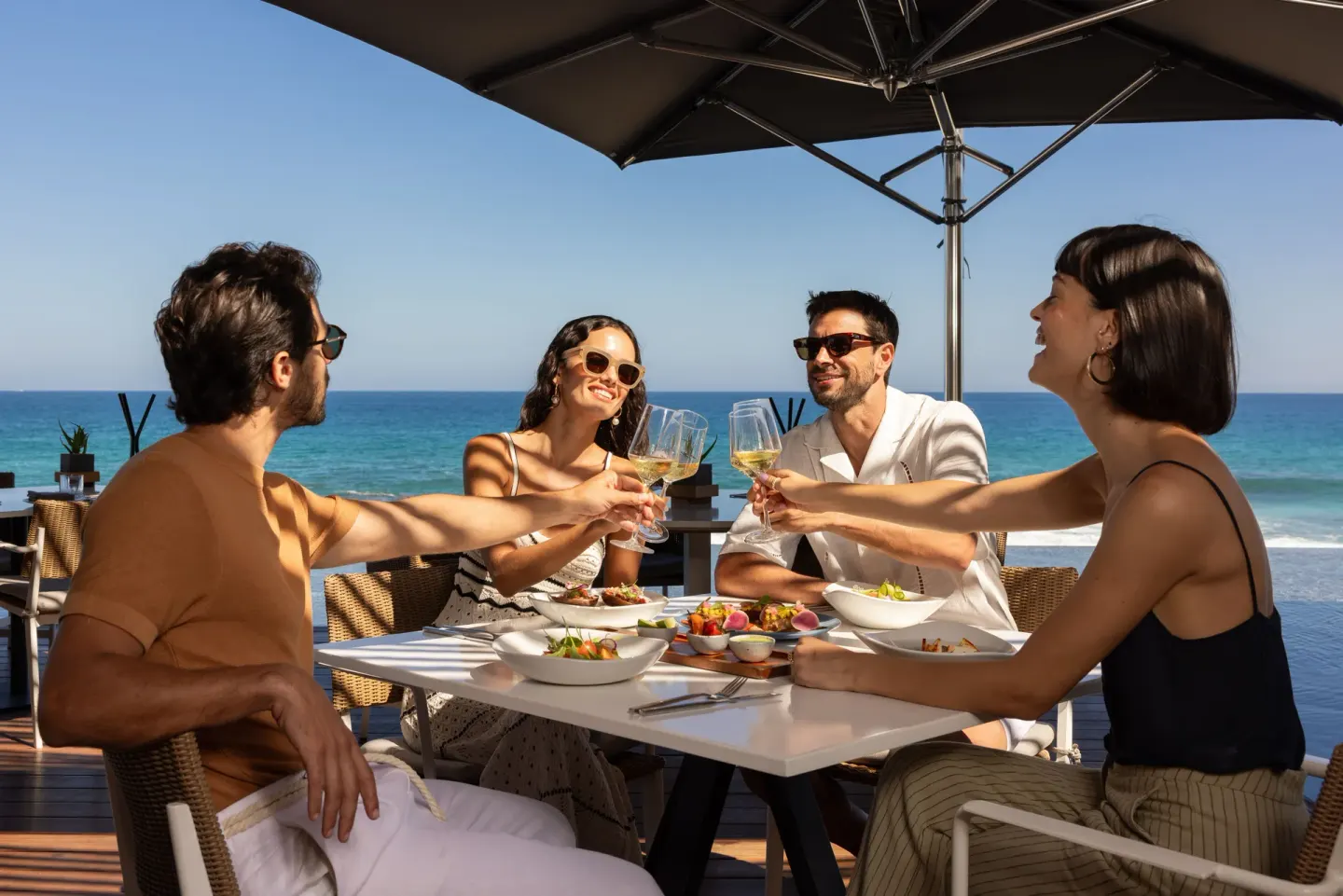 Guests toast over lunch on an oceanfront terrace at The Club at Solaz.