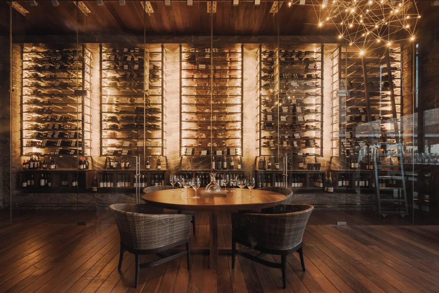 Glass-walled wine room with a round tasting table at The Club at Solaz.
