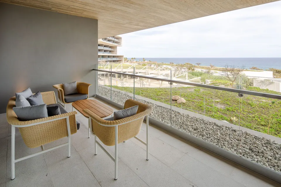 Furnished ocean-view balcony of a One Bedroom Villa at The Club at Solaz with cushioned chairs.