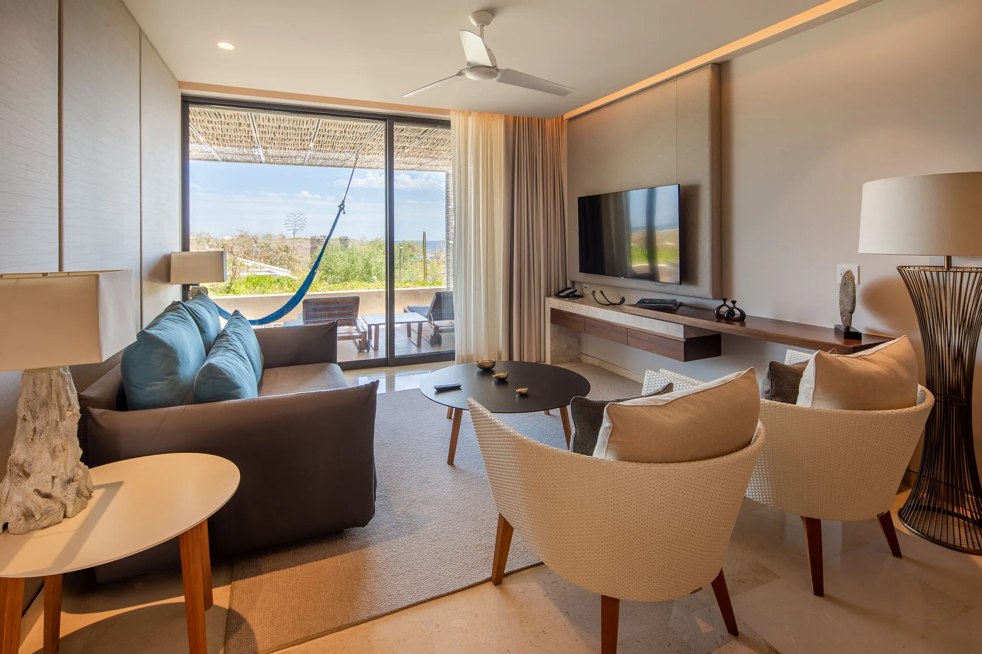 Living room in a Three Bedroom Villa at The Club at Solaz with sofa, chairs, TV, and terrace view.