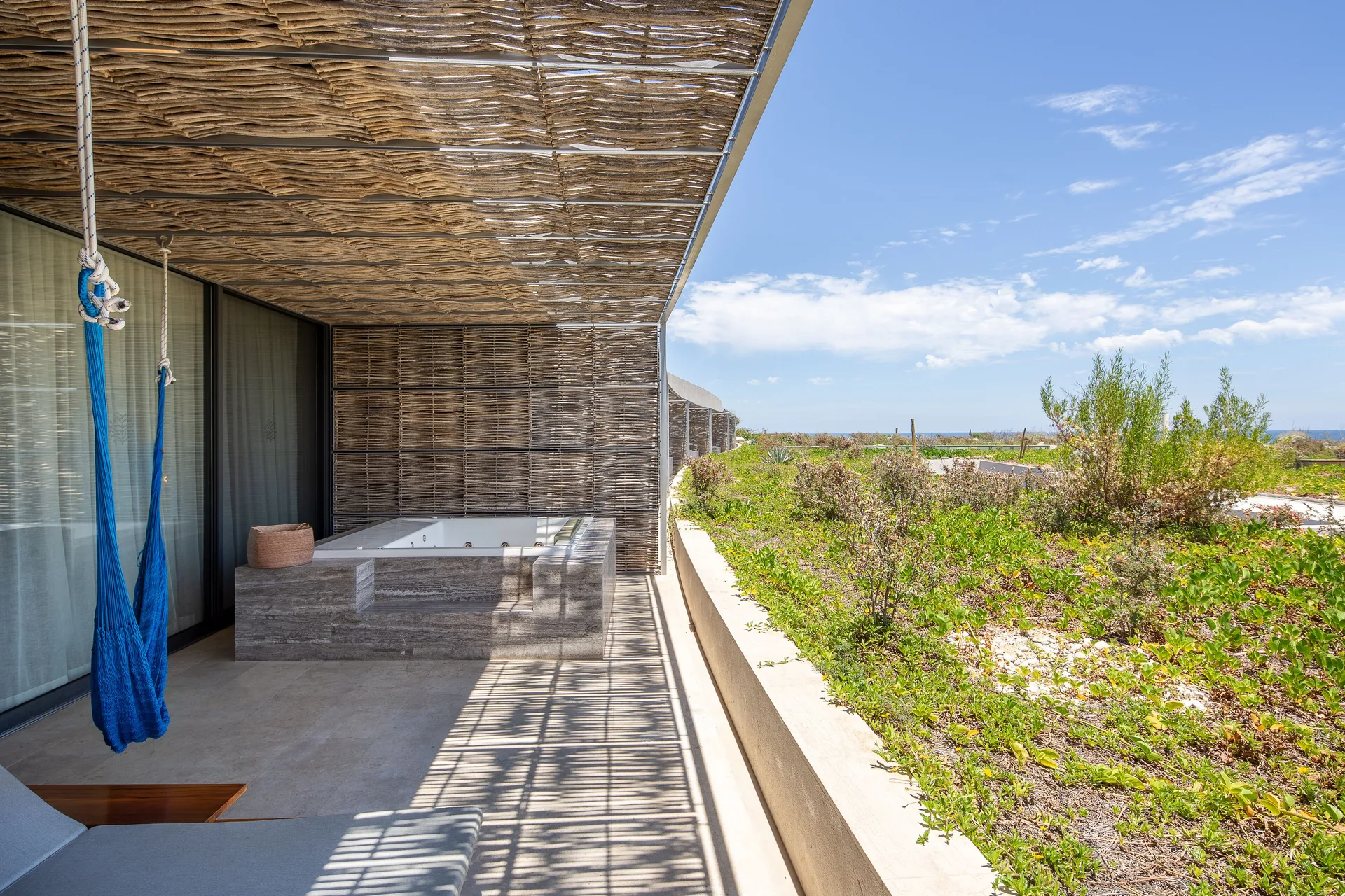 Villa terrace at The Club at Solaz with hot tub, blue hammock, lounge chair, and garden view.