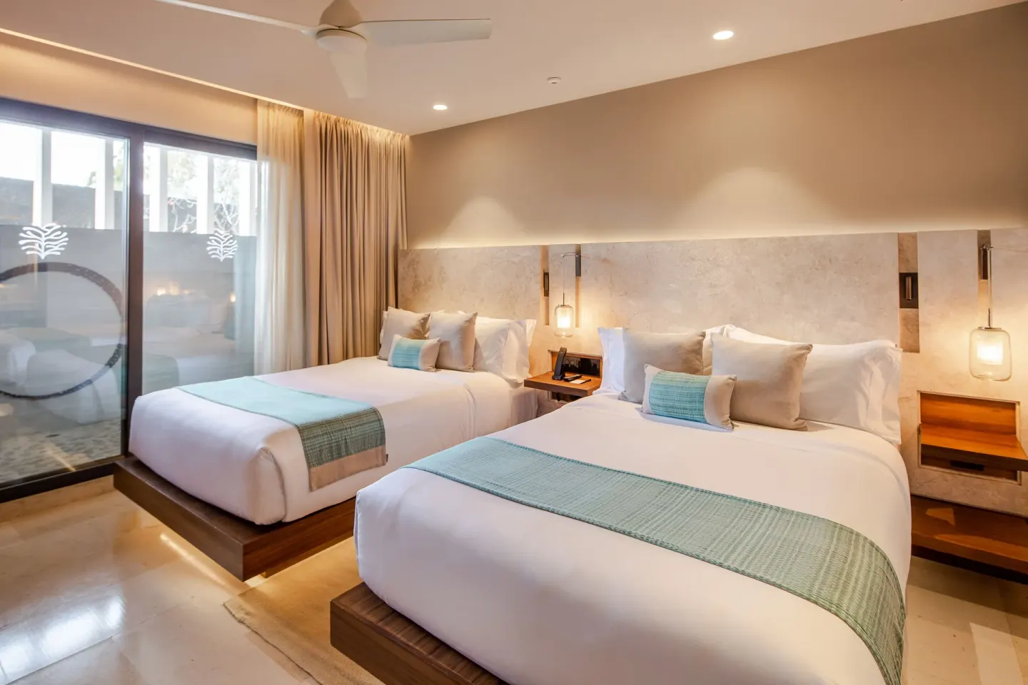Two queen beds in an ocean-view villa bedroom at The Club at Solaz.