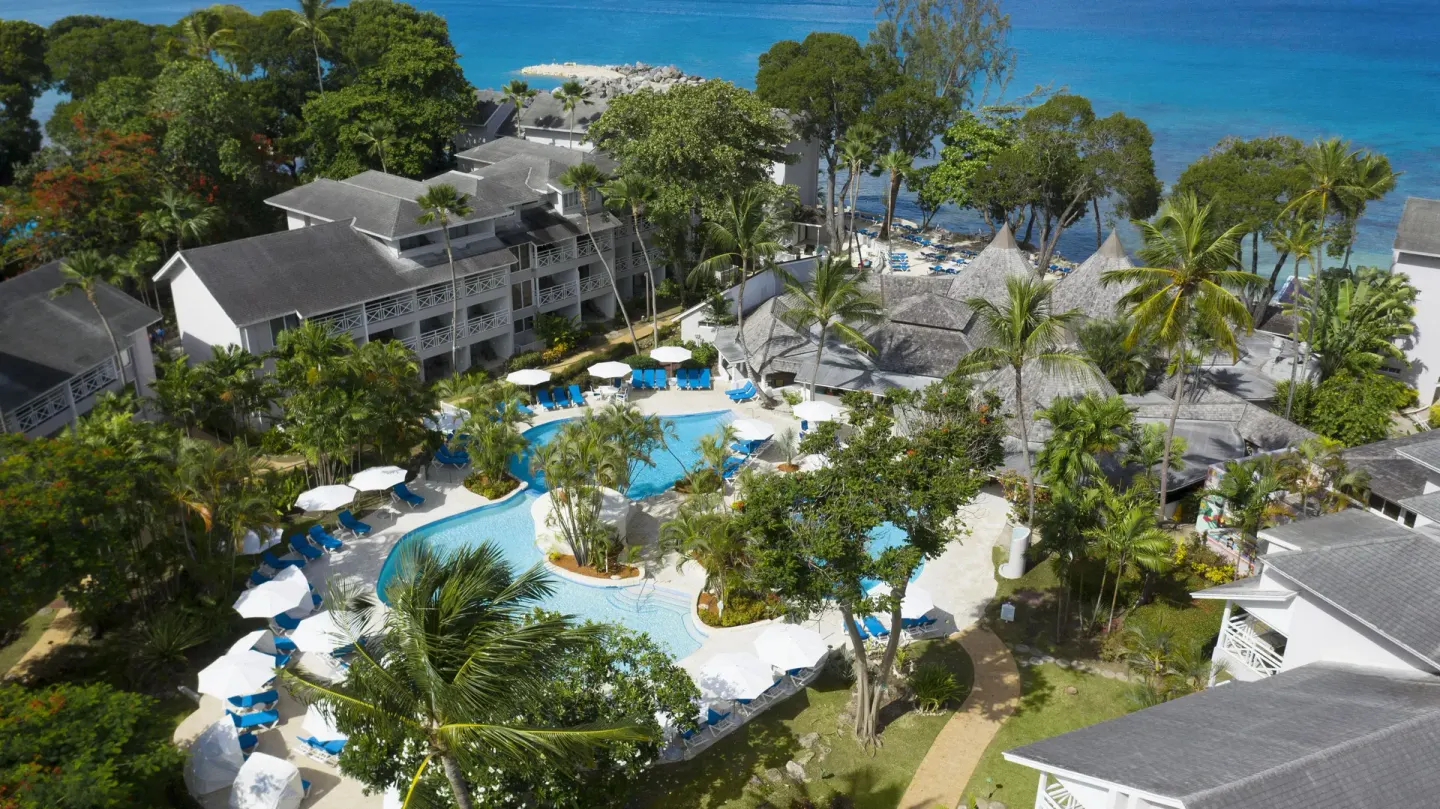 Aerial resort view with pools, palms and ocean at The Club, Barbados Resort & Spa.