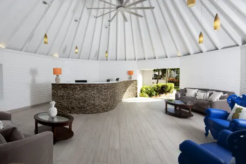 Open lobby with curved reception desk and lounge seating at The Club, Barbados Resort & Spa.