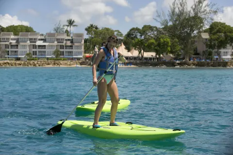 Guests paddleboarding on turquoise water at The Club, Barbados Resort & Spa.
