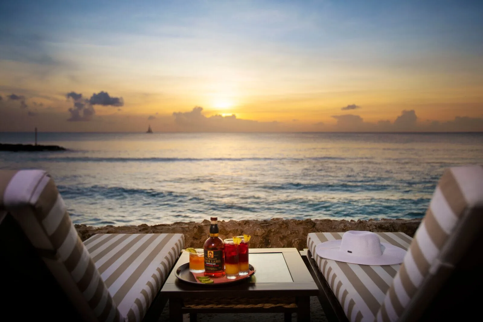 Seaside loungers with cocktails at sunset at The Club, Barbados Resort & Spa.