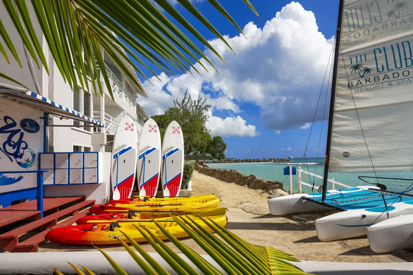 Kayaks, paddleboards, and sailboats by the beach at The Club, Barbados Resort & Spa.