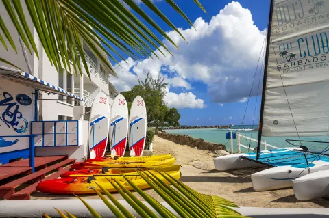 Kayaks, paddleboards, and sailboats by the beach at The Club, Barbados Resort & Spa.
