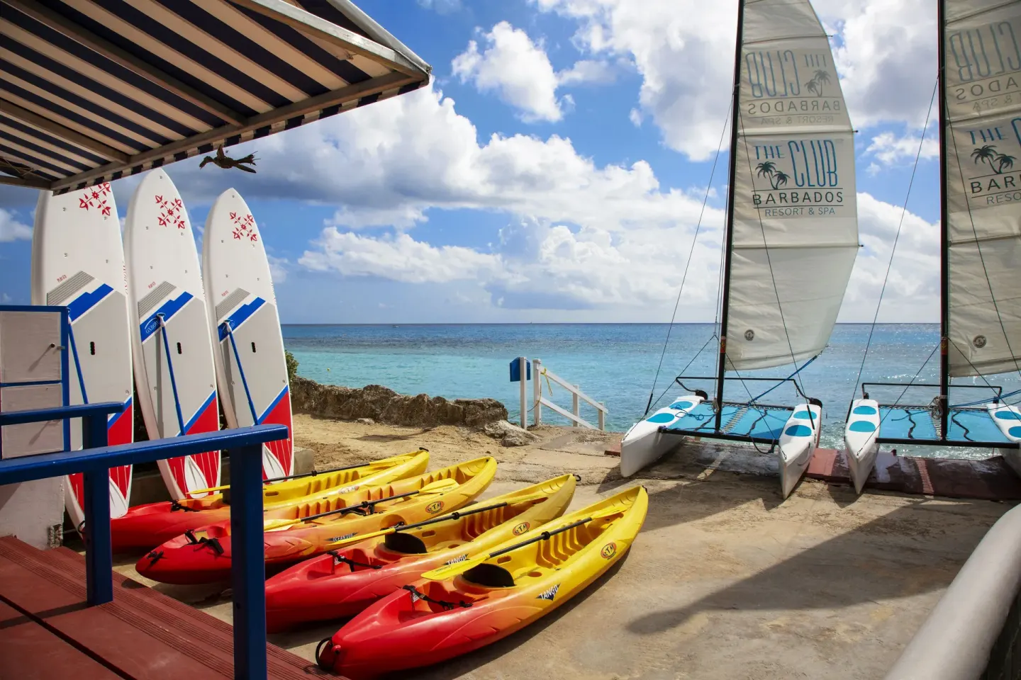 Kayaks, boards, and sailboats by the sea at The Club, Barbados Resort & Spa.