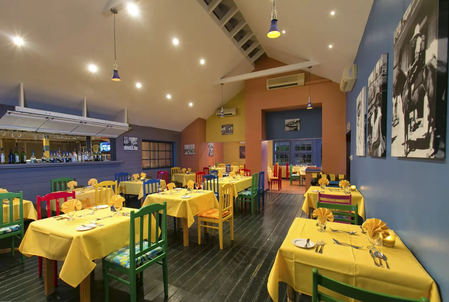 Restaurant interior with colorful chairs and wall photos at The Club, Barbados Resort & Spa.