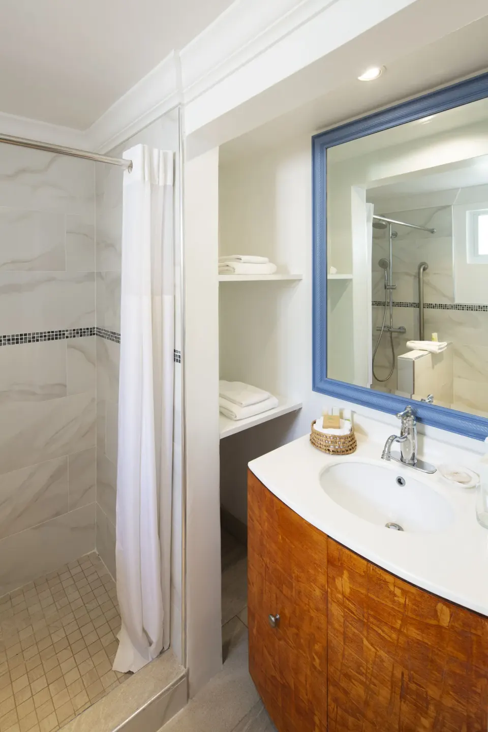 Garden View room bathroom with shower and blue-framed mirror at The Club, Barbados Resort & Spa.