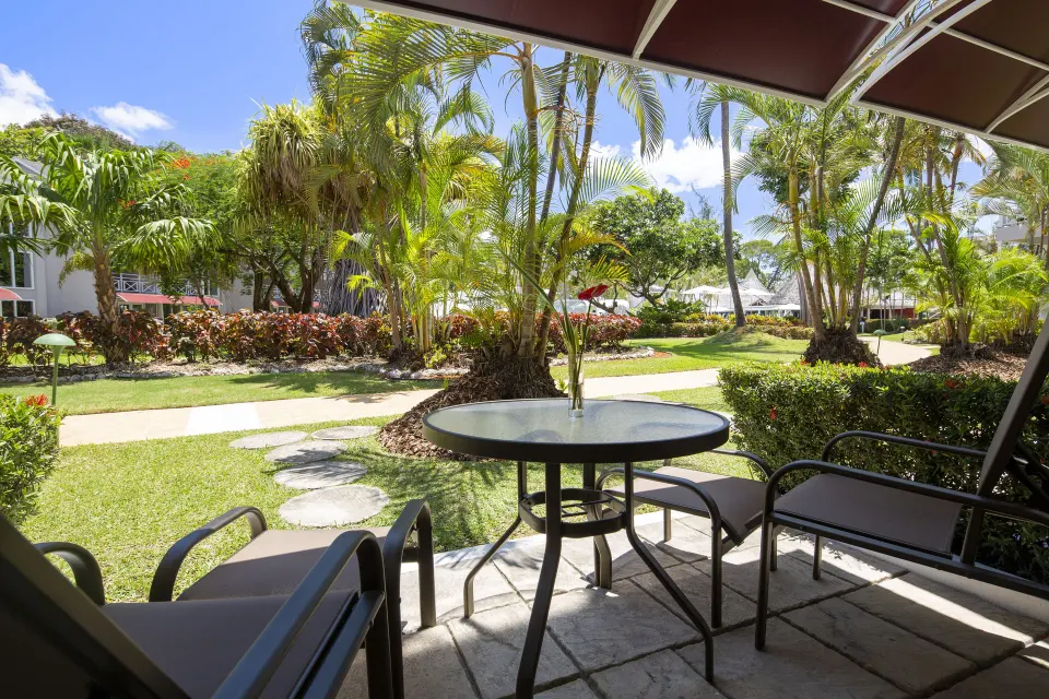 Garden View room patio with table and palm garden view at The Club, Barbados Resort & Spa.