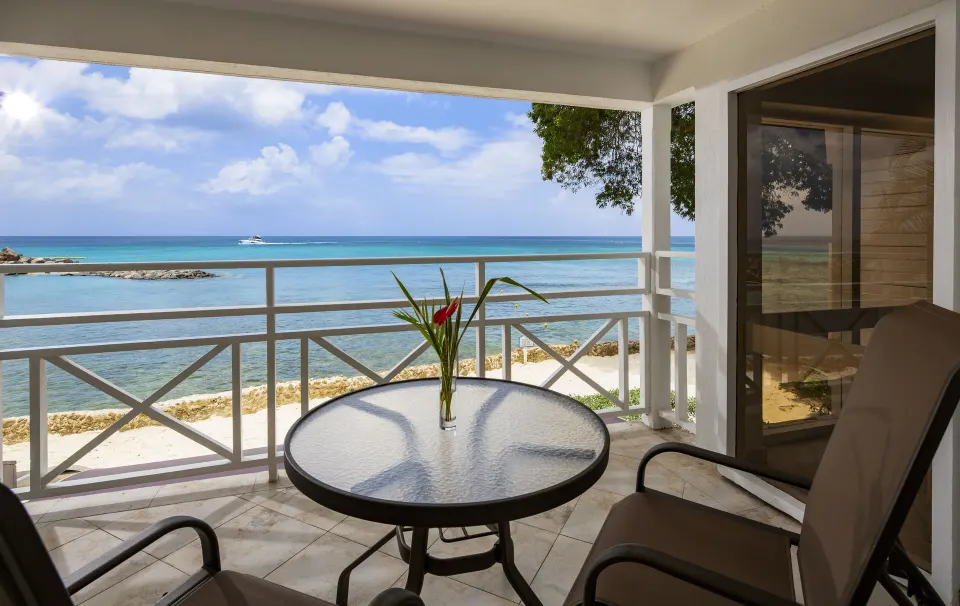 One Bedroom Oceanfront Suite balcony with table and ocean view at The Club, Barbados Resort & Spa.