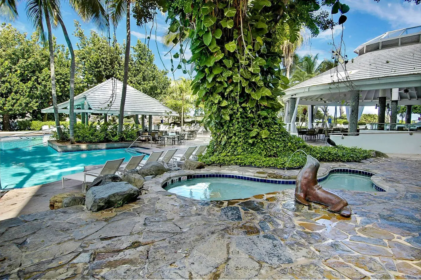 Pool area with hot tubs, palms, and pavilion at The Condado Plaza Hotel.