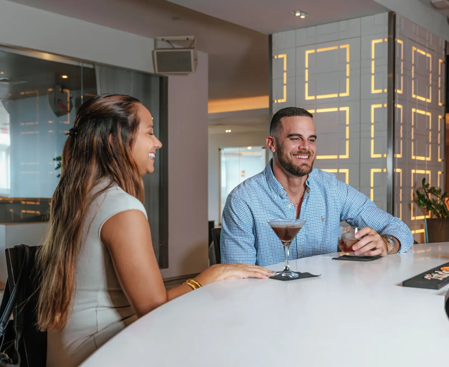 Guests enjoying cocktails at a white bar inside The Condado Plaza Hotel.