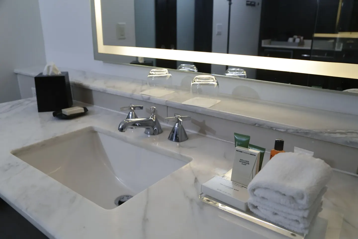 Marble bathroom vanity with sink, mirror, towels, and amenities at The Condado Plaza Hotel.