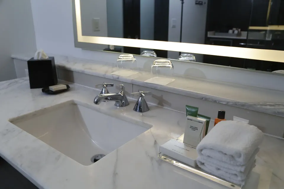 Marble bathroom vanity with sink, mirror, towels, and amenities at The Condado Plaza Hotel.