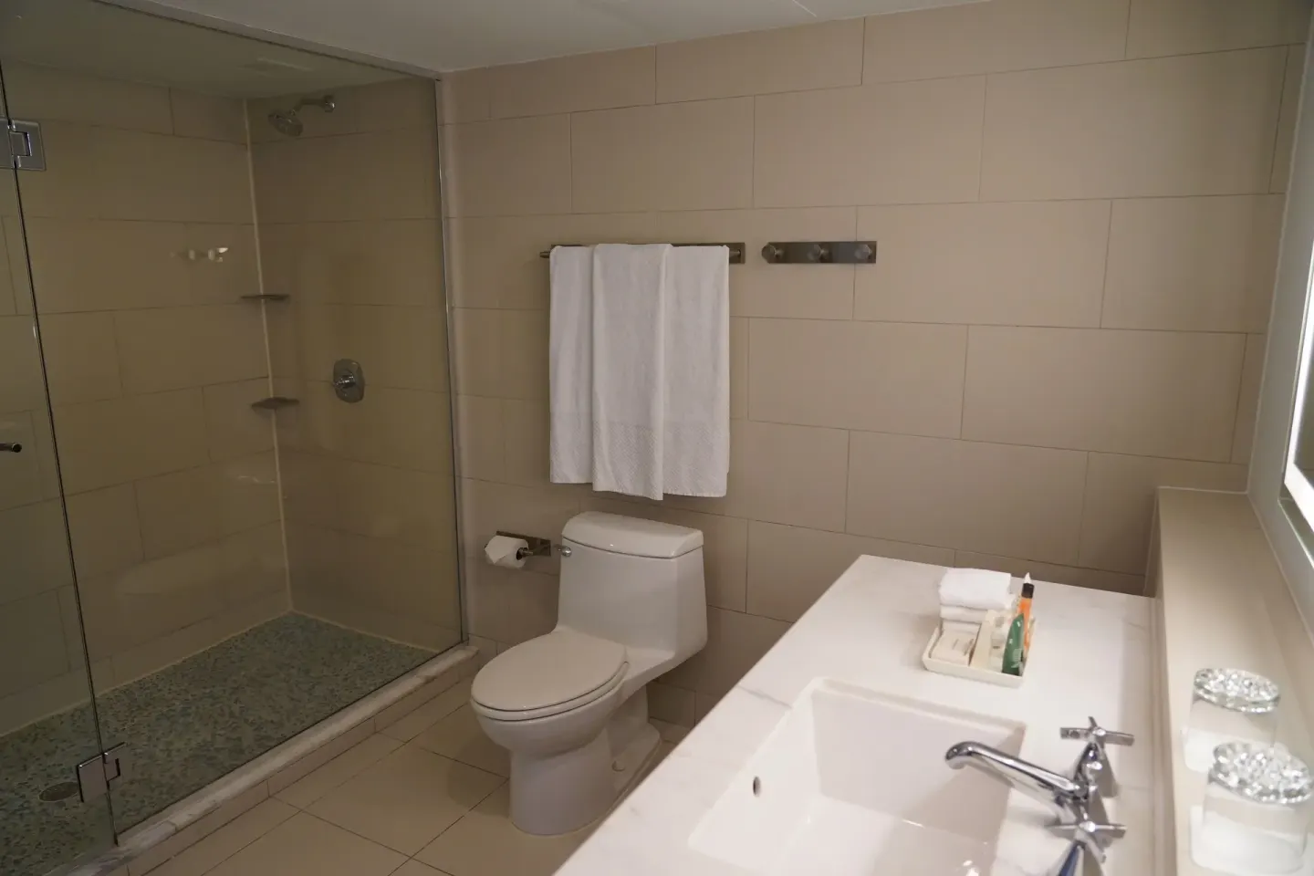 Deluxe Room bathroom with glass shower, toilet, vanity, and towels at The Condado Plaza Hotel.
