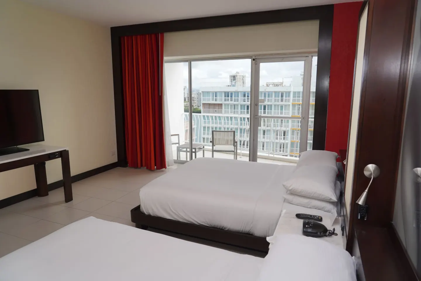 Two-bed Deluxe Room with balcony doors and city-facing view at The Condado Plaza Hotel.
