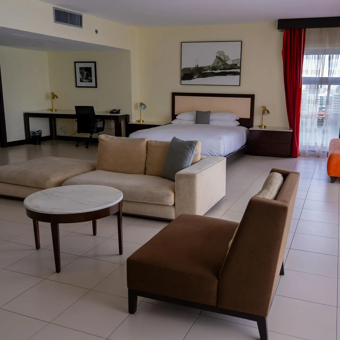 Junior Suite balcony with king bed, seating area, desk, and red curtains at The Condado Plaza Hotel.
