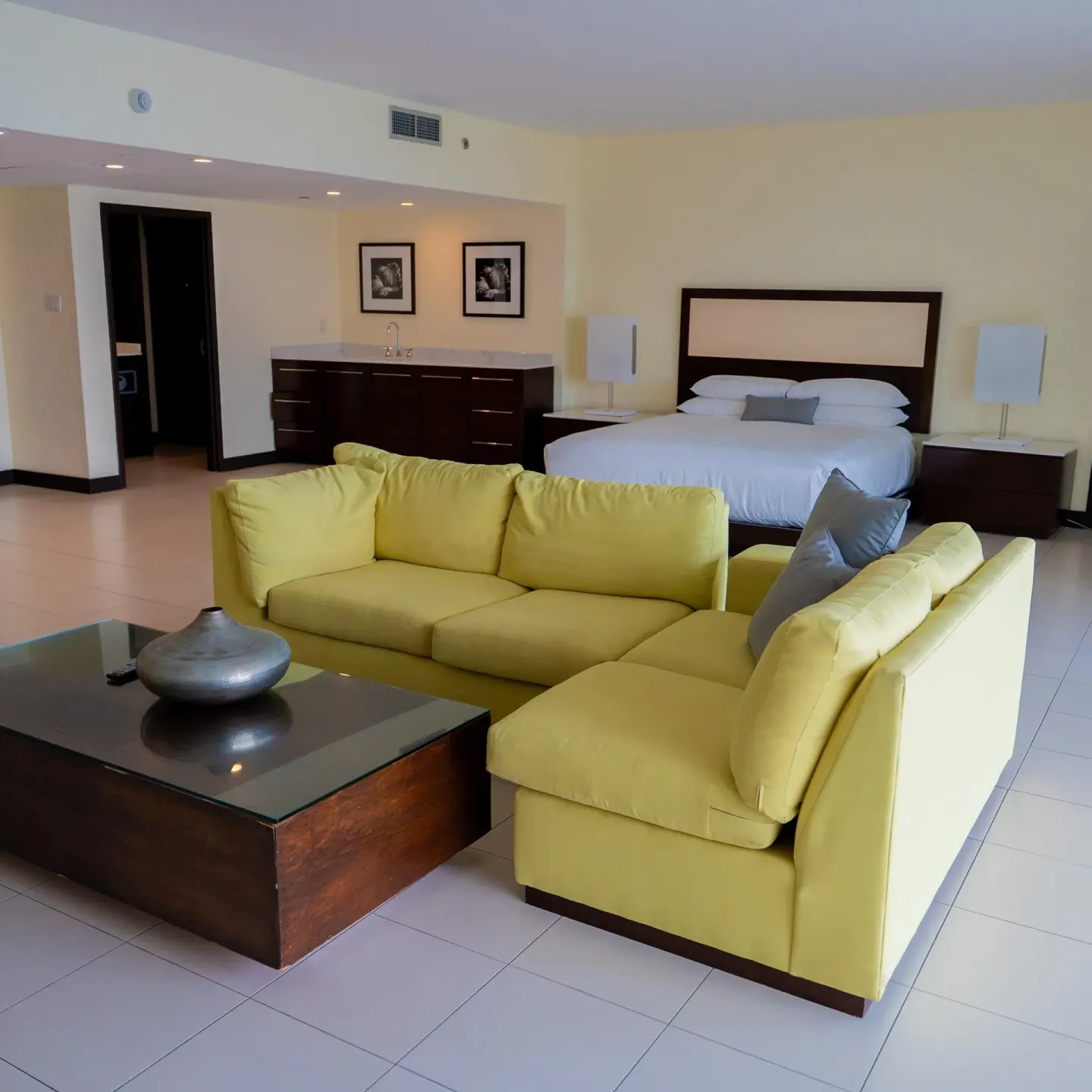 Junior Suite balcony with king bed, yellow sectional, and wet bar at The Condado Plaza Hotel.