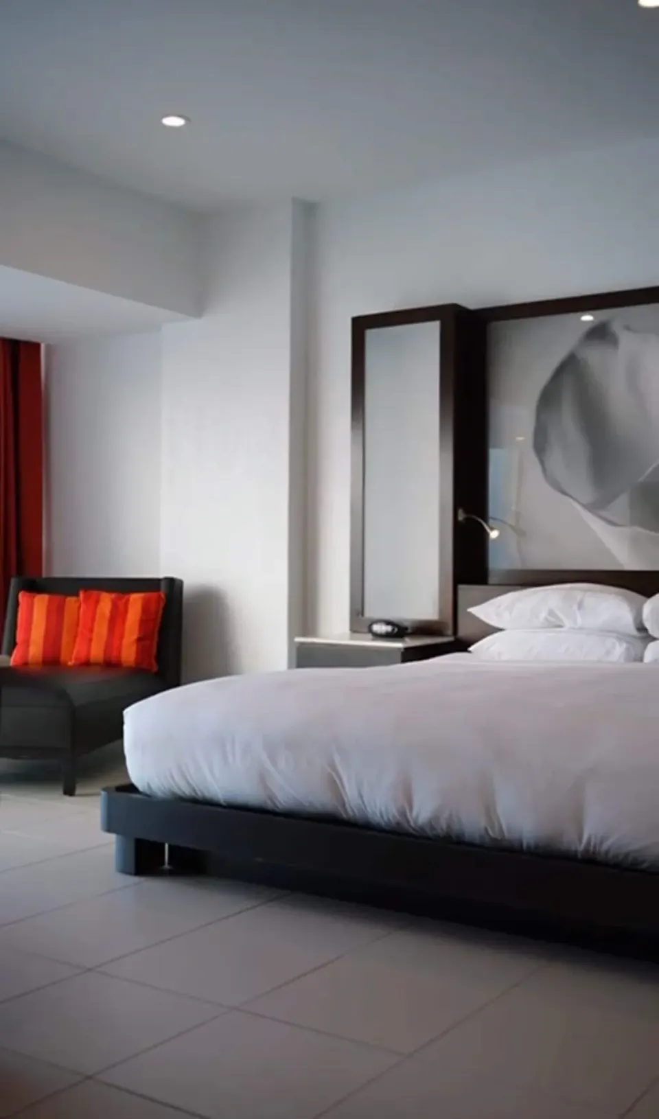 Guest room bed with bedside table and lounge chair at The Condado Plaza Hotel.