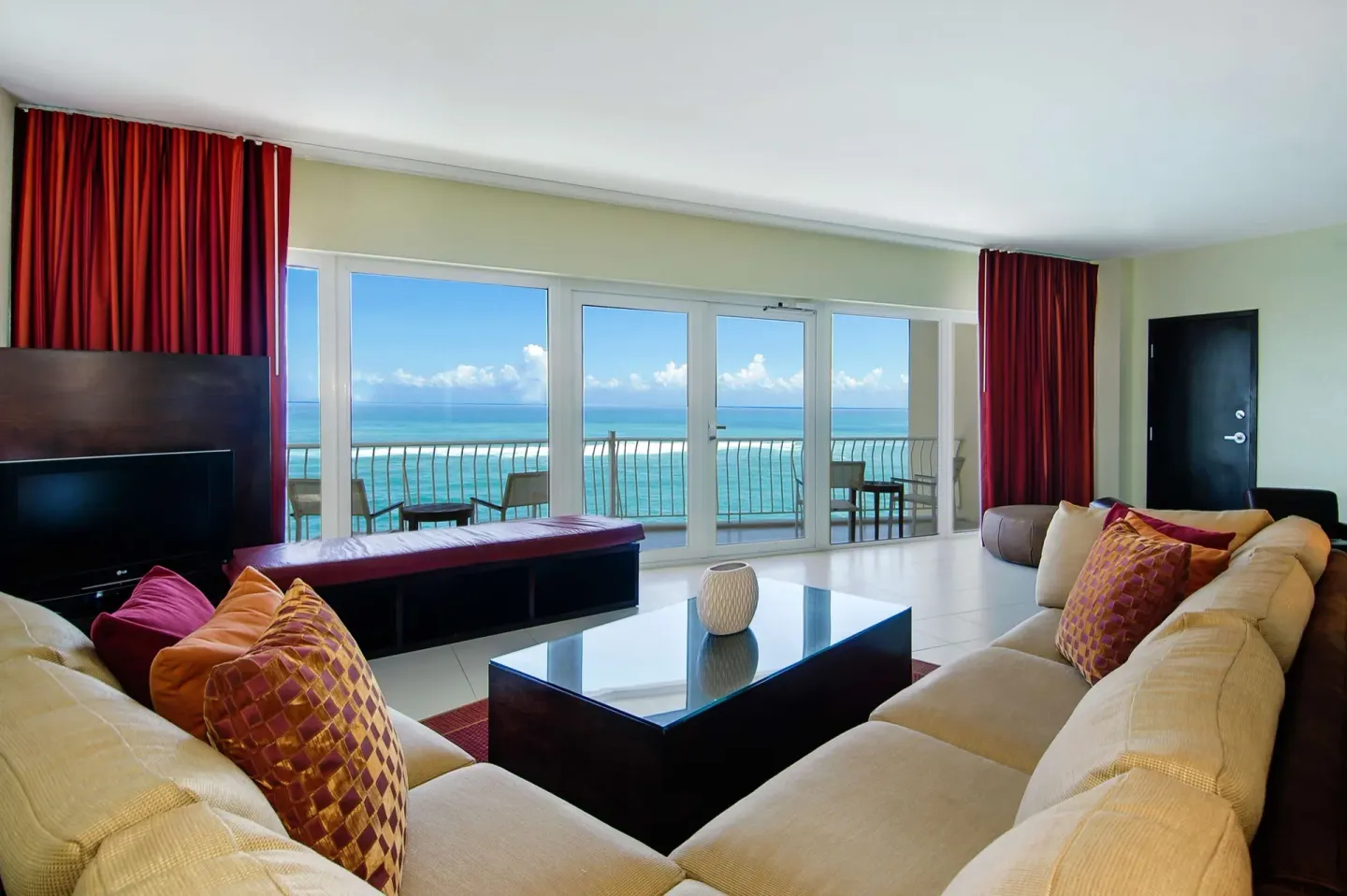 Oceanfront penthouse suite living room with sofas, TV, balcony, and sea view at The Condado Plaza Hotel.