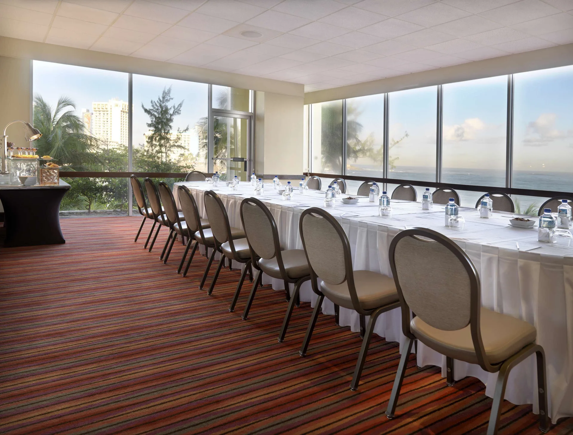 Meeting room with long tables, water bottles, and ocean-view windows at The Condado Plaza Hotel.