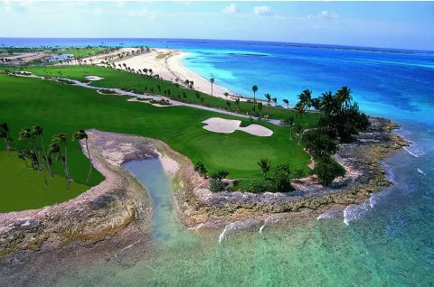 Aerial view of a beachfront golf course and turquoise ocean at The Coral at Atlantis.