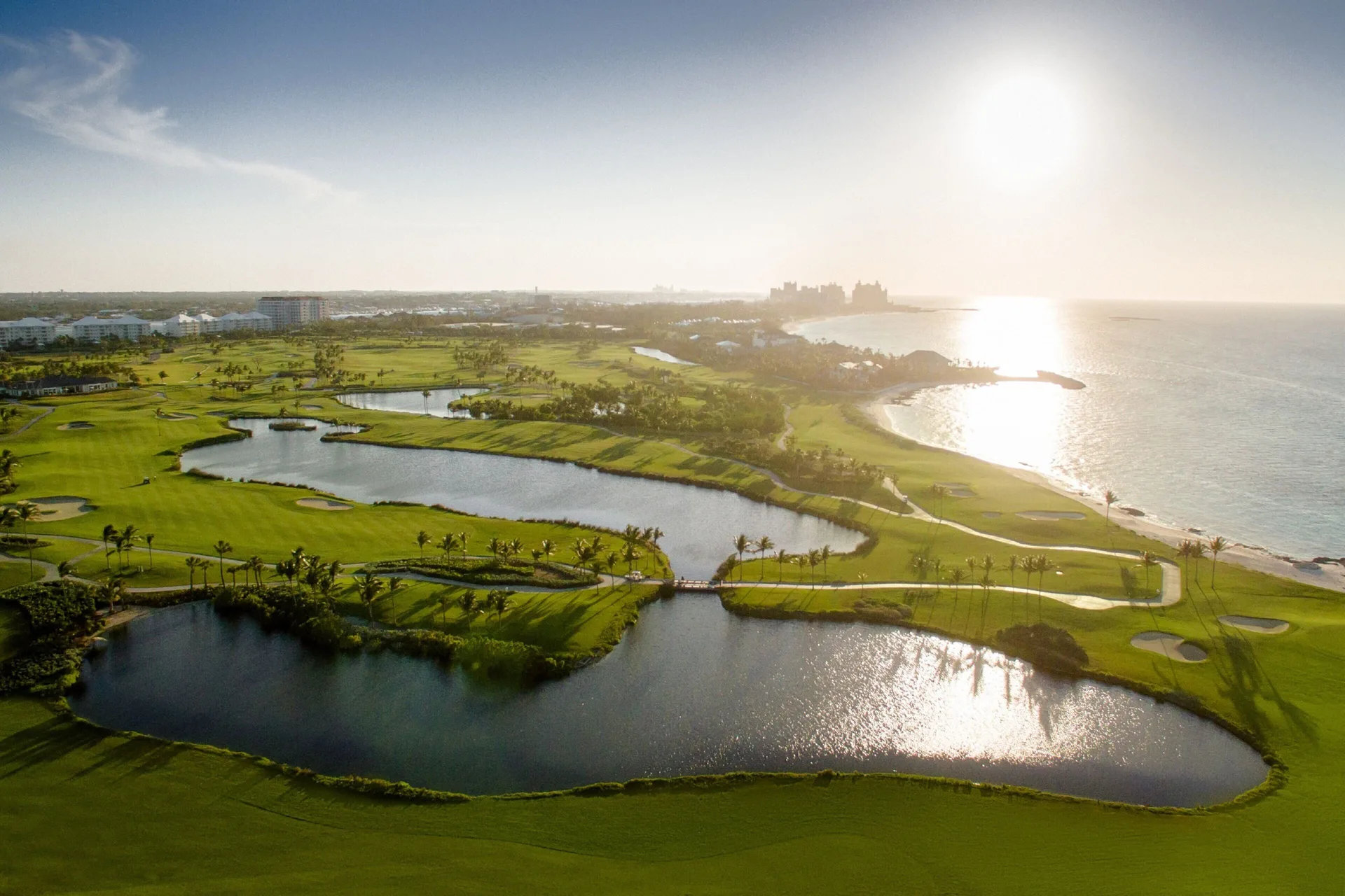 Aerial view of golf greens, ponds, and coastline near The Coral at Atlantis.