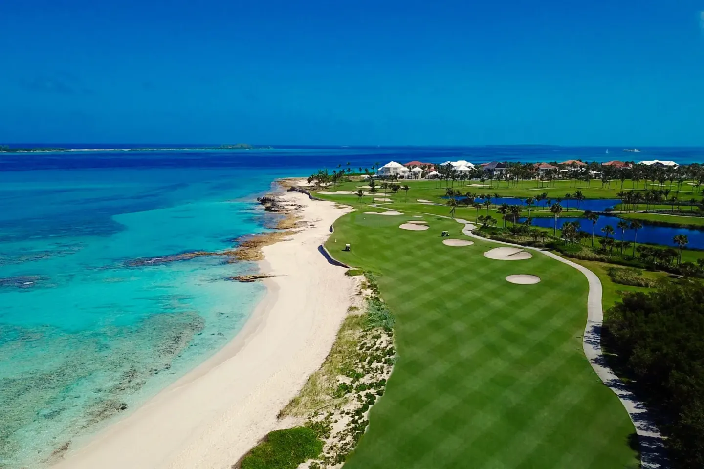 Aerial view of a beachfront golf course beside turquoise water at The Coral at Atlantis.