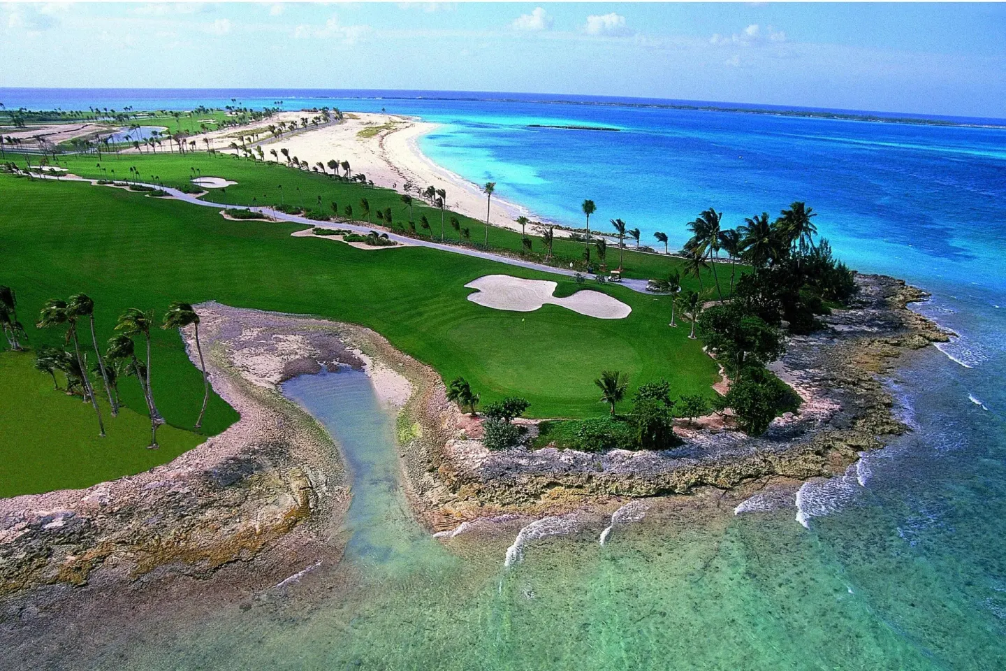 Aerial coastline view with golf greens and turquoise water at The Coral at Atlantis.