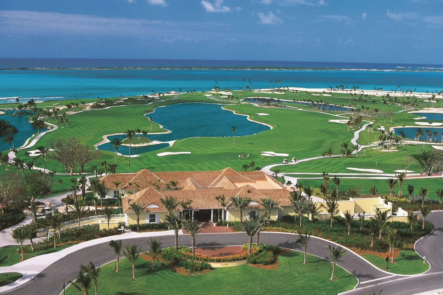 Aerial view of golf fairways, lakes, palms, and ocean at The Coral at Atlantis.