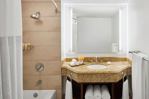 Guest bathroom with illuminated mirror and tub-shower at The Coral at Atlantis.