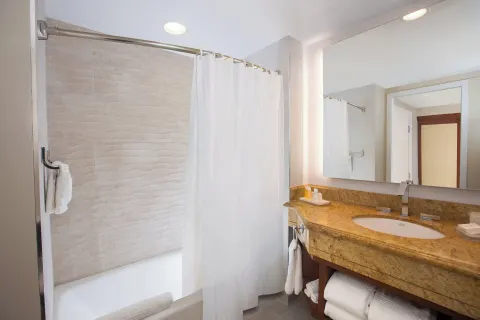 Guest bathroom with tub, curtain, and stone vanity at The Coral at Atlantis.