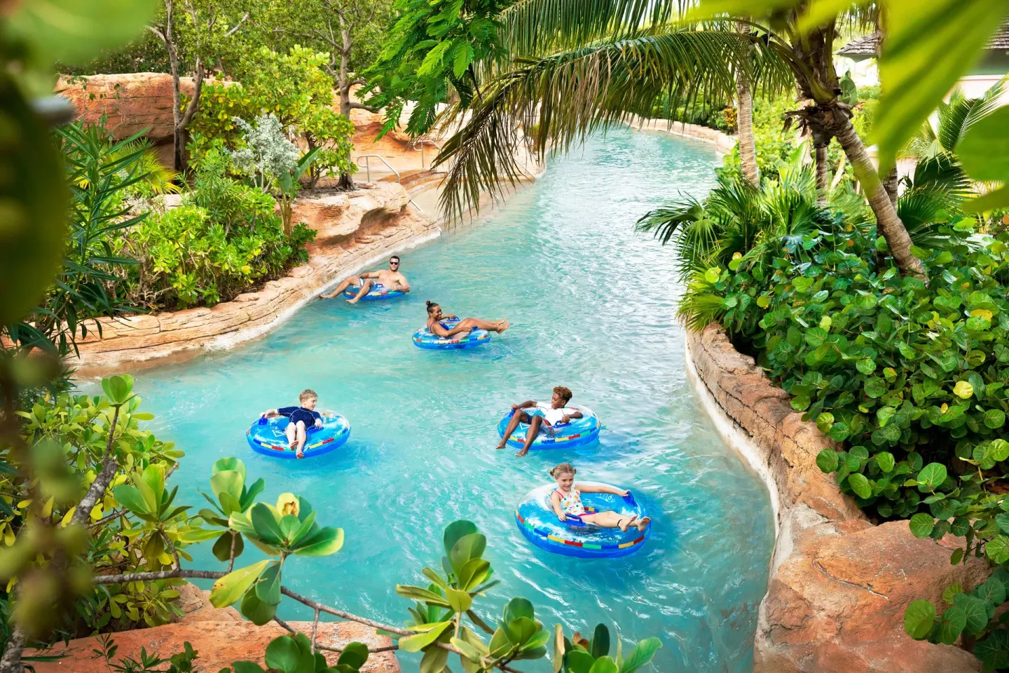Guests float on blue inner tubes along a landscaped lazy river at The Coral at Atlantis.