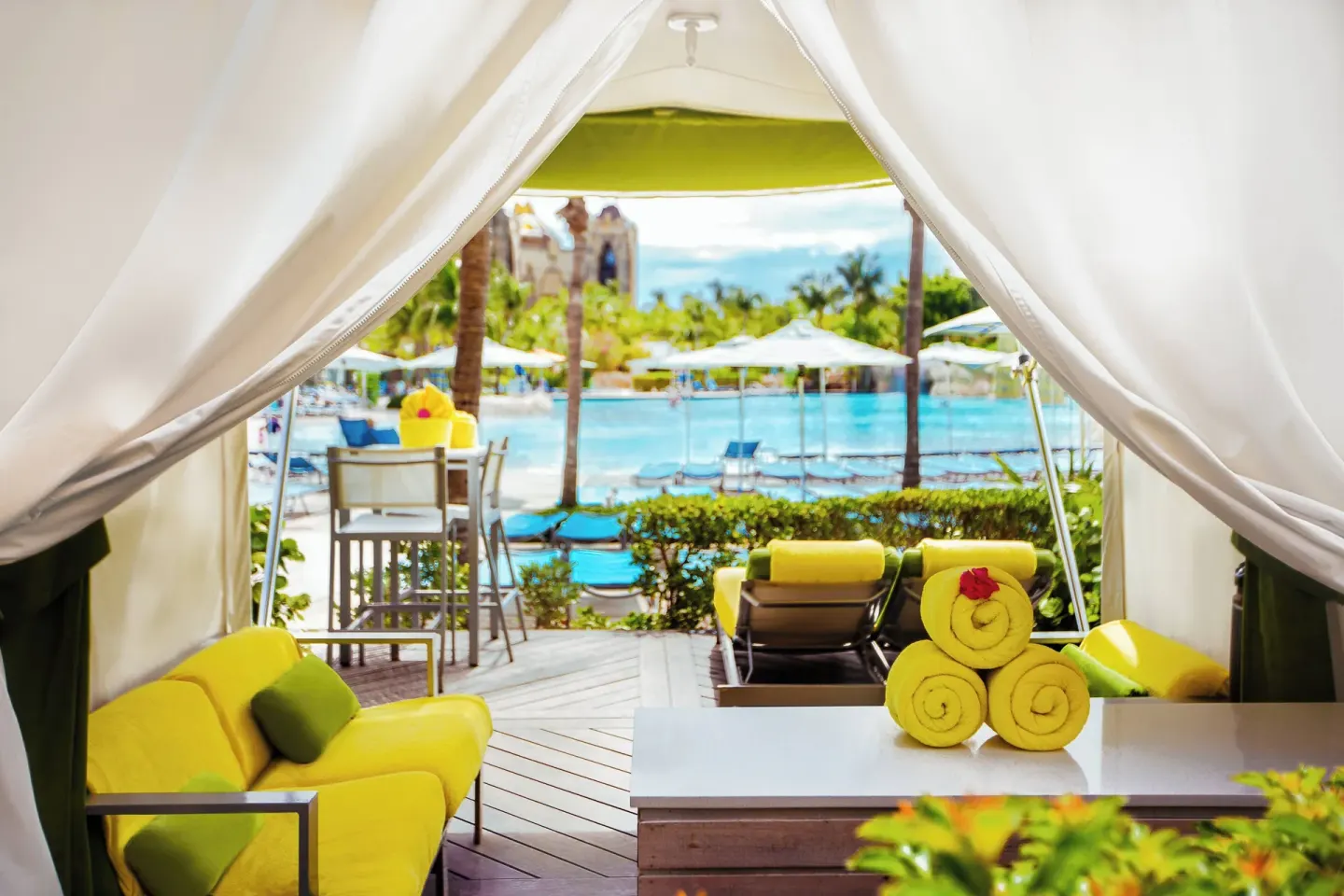 Pool cabana with yellow cushions and towels overlooking loungers at The Coral at Atlantis.