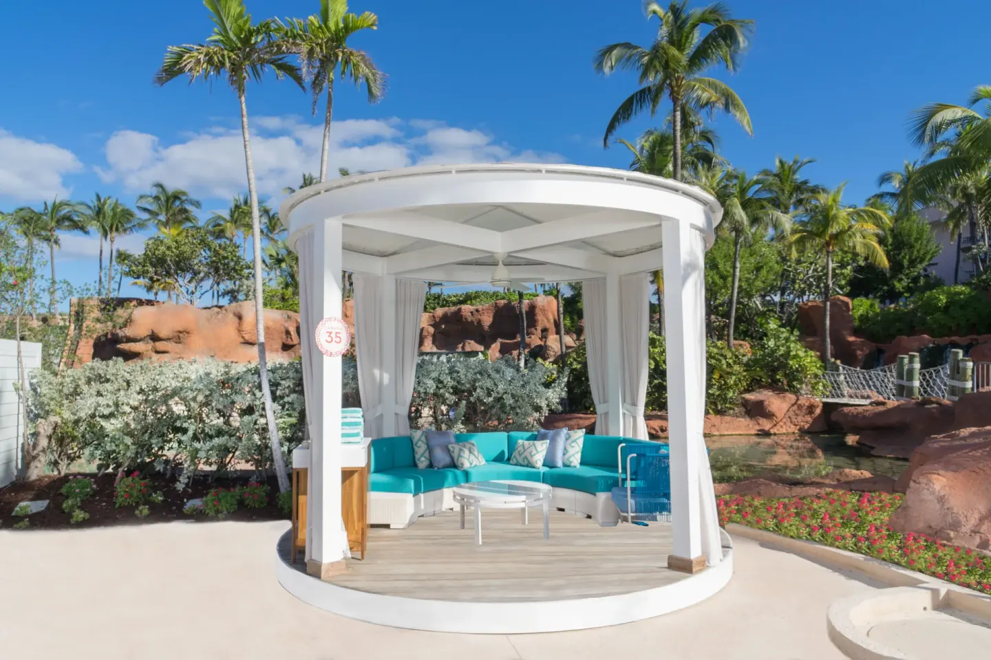 White poolside cabana with turquoise seating and palms at The Coral at Atlantis.