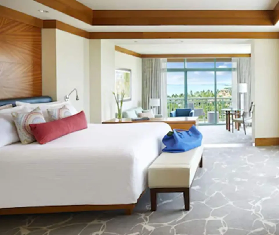 Indigo Suite king bed with bench and balcony seating beyond at The Cove at Atlantis.