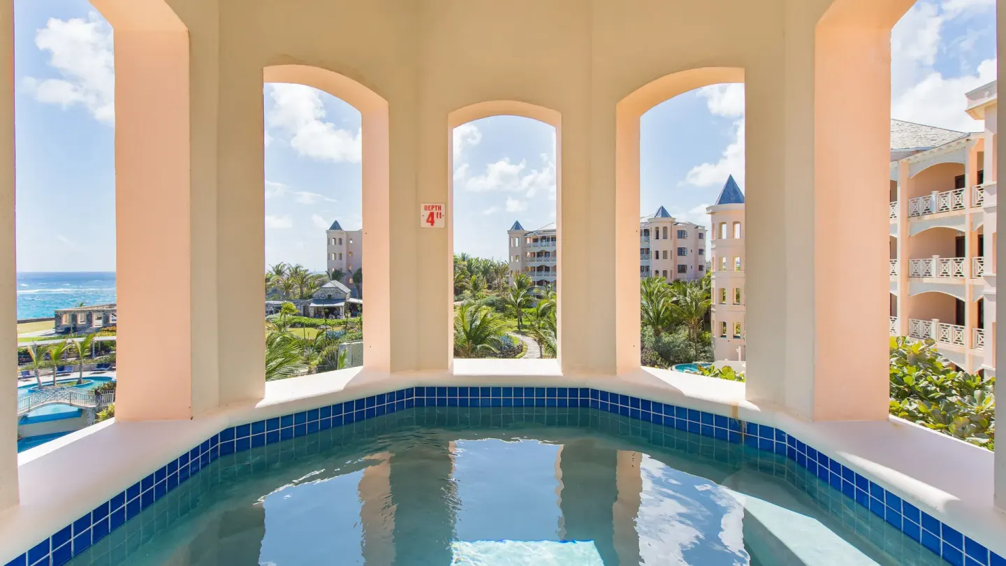 An arched plunge pool balcony overlooks the gardens and ocean at The Crane Resort.