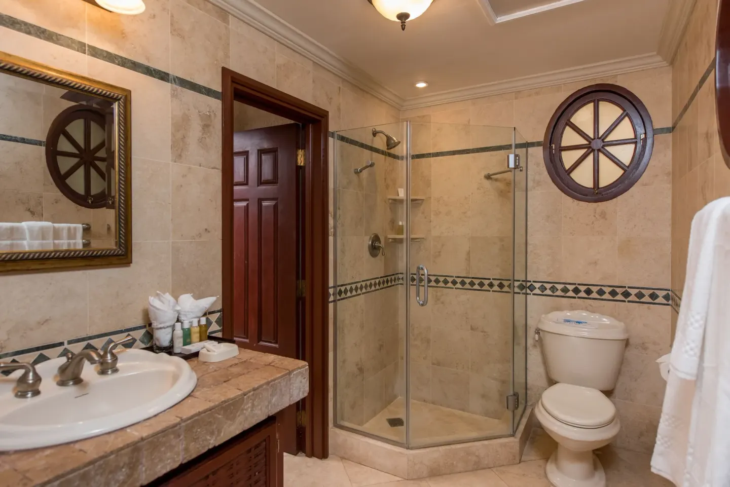 Bathroom with glass shower, vanity and round window at The Crane Resort.