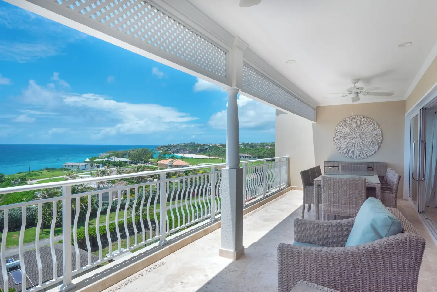Covered balcony with wicker seating and coastal view at The Crane Resort.