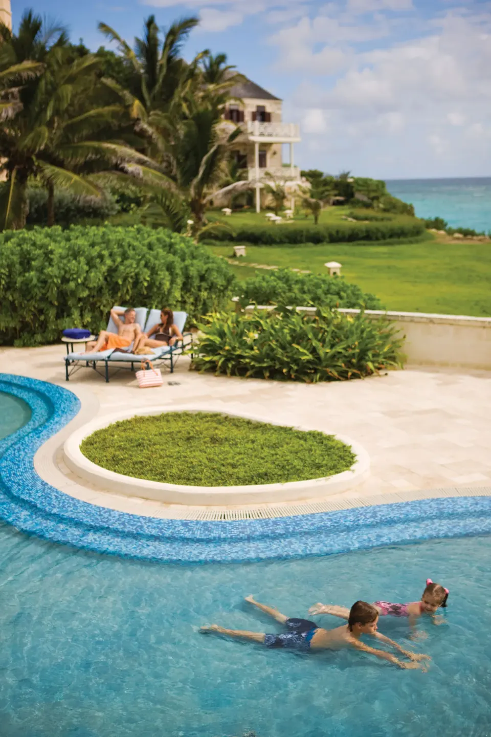 Guests swim and lounge beside a curved pool at The Crane Resort.