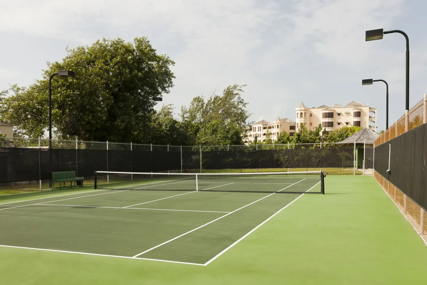 Outdoor tennis court with fencing and benches at The Crane Resort.