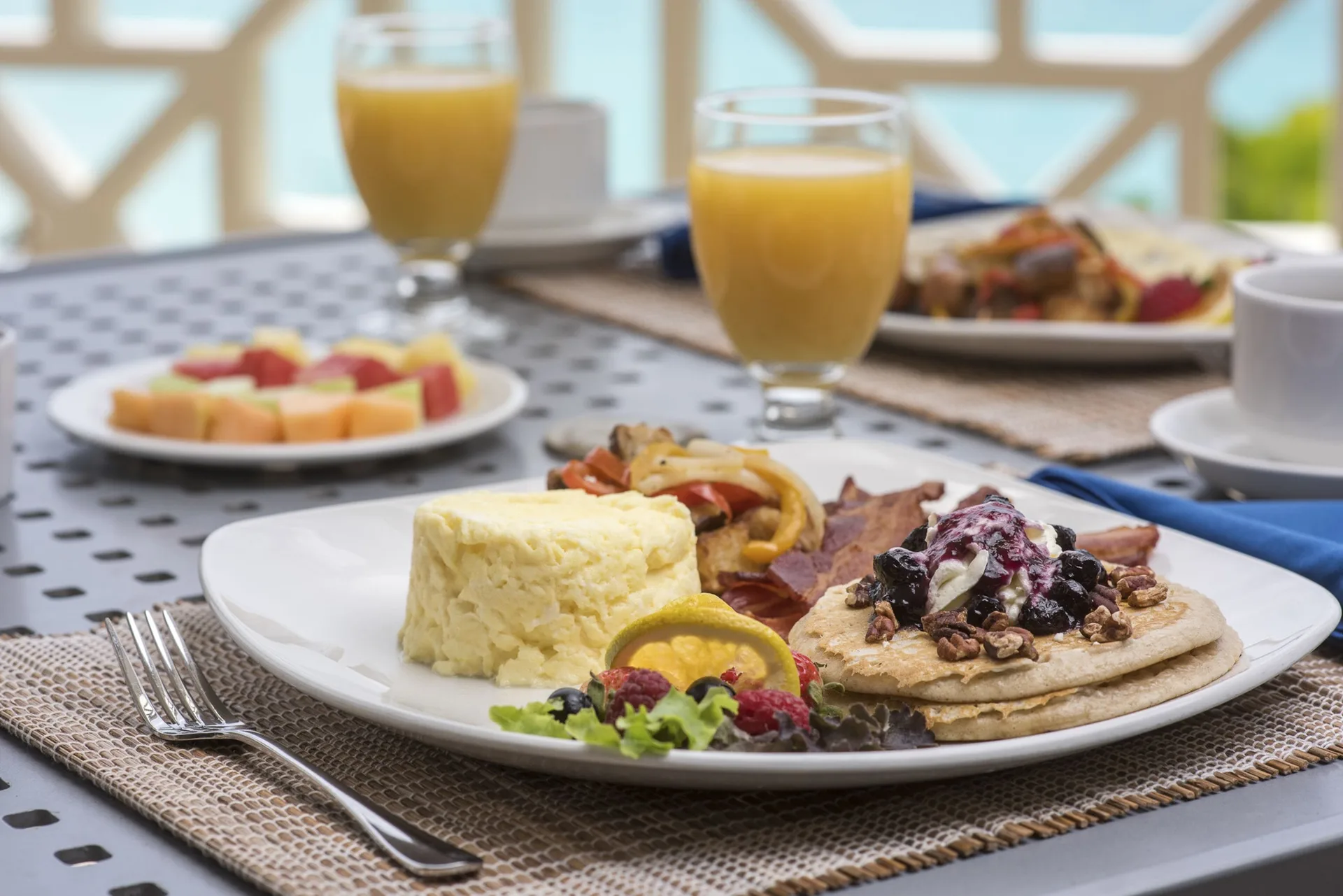 Breakfast plates with juice set on an ocean-view table at The Crane Resort.