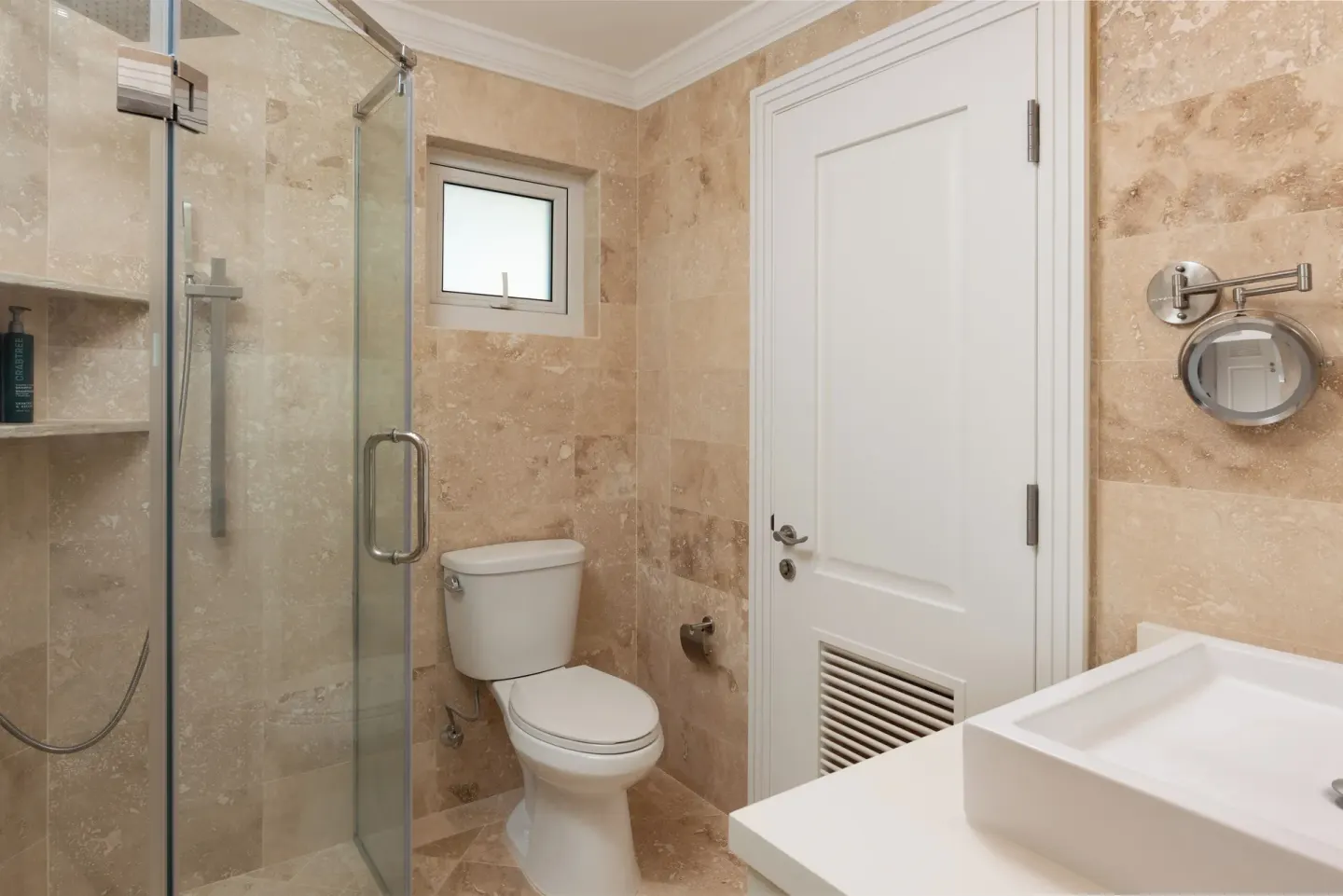 Junior Studio Suite bathroom with glass shower, toilet, vanity, and stone tile at The Crane Resort.
