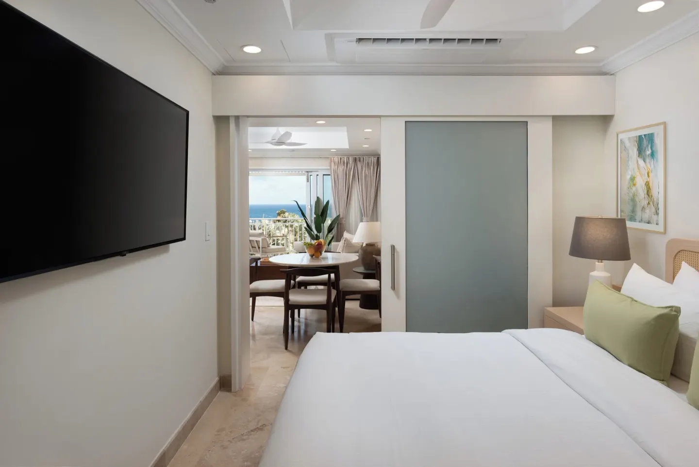 Junior Studio Suite bedroom with TV, sitting area, and partial ocean view at The Crane Resort.