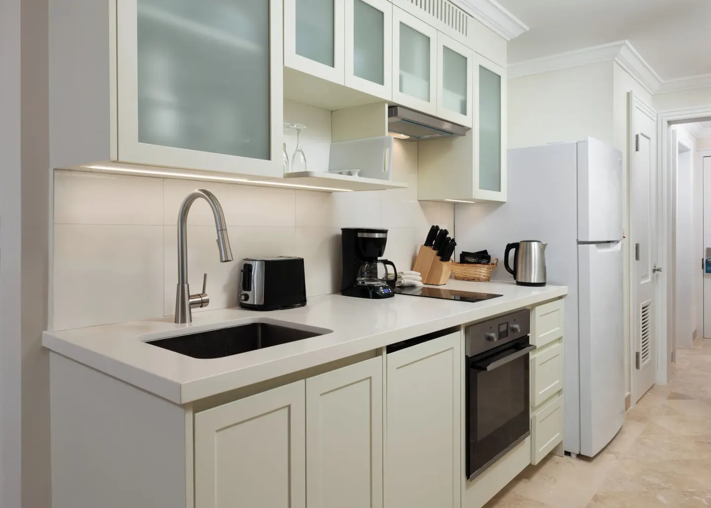 Junior Studio Suite kitchenette with sink, cooktop, oven, and refrigerator at The Crane Resort.