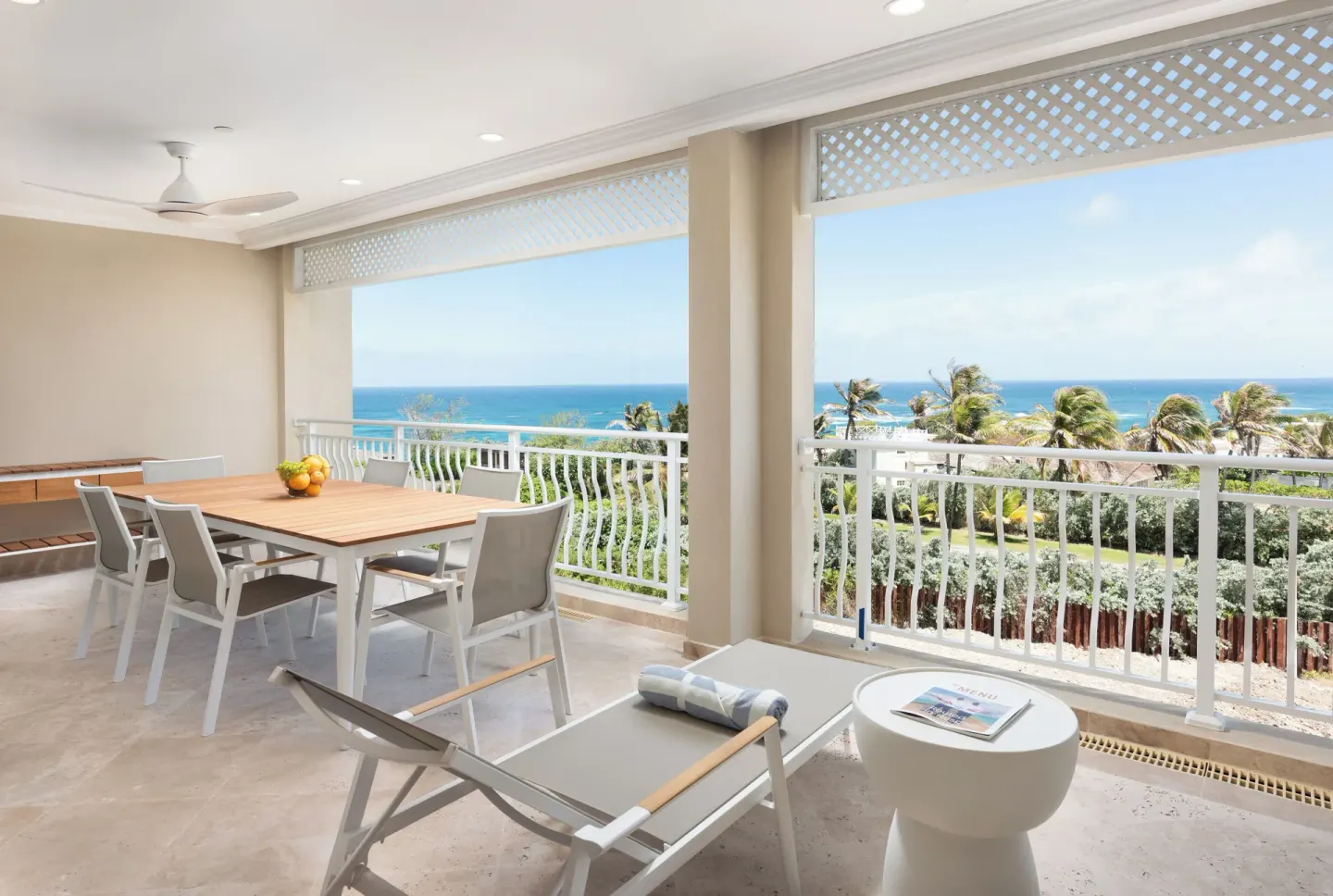 Covered balcony with dining table, lounge chair, and ocean view at The Crane Resort.