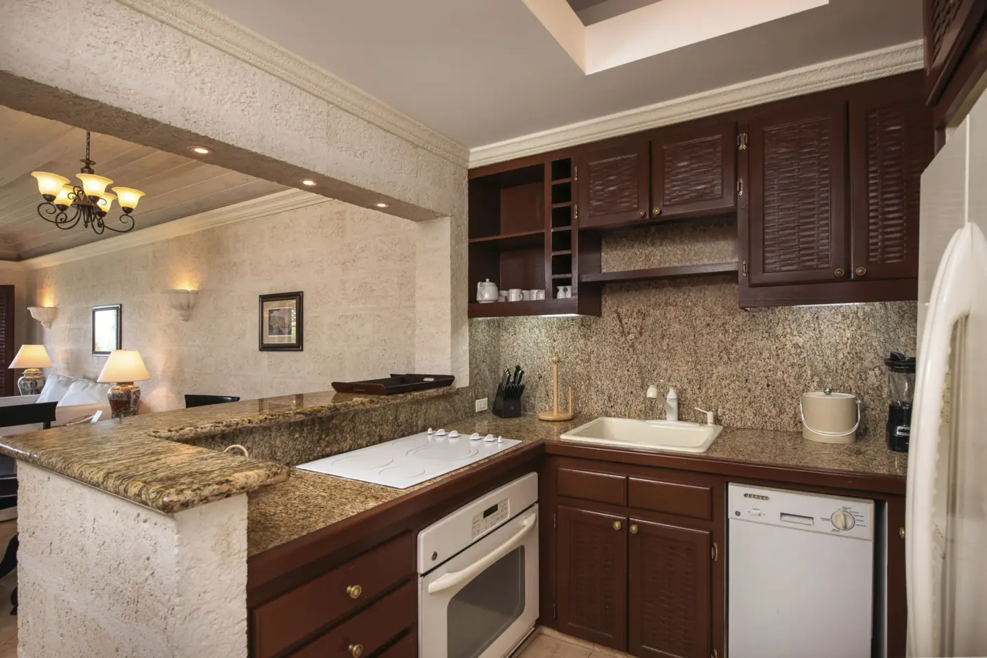 Suite kitchen at The Crane Resort with granite counters, wood cabinets, oven, sink, and dishwasher.